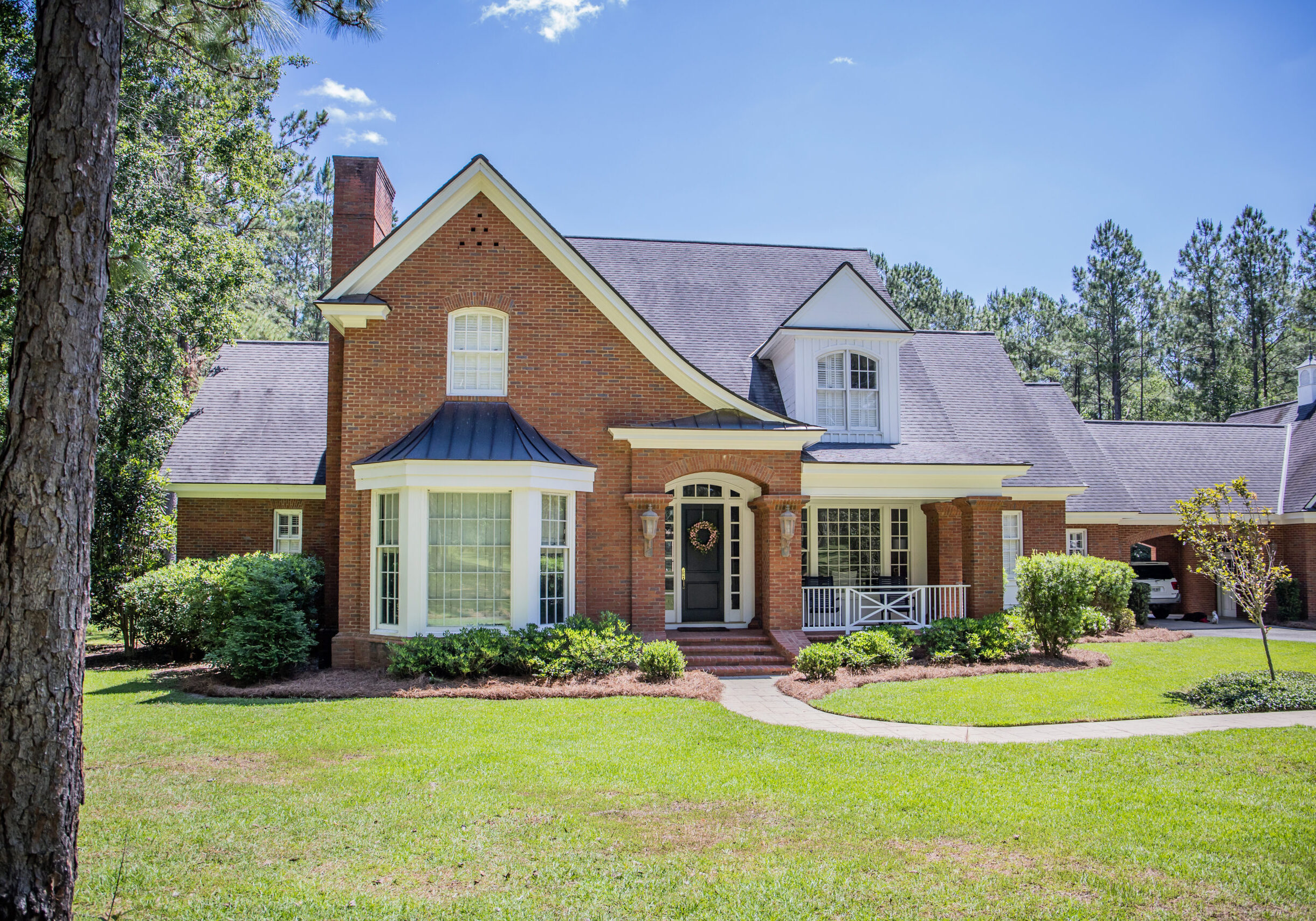 Traditional brick home with large windows and covered porch in the Atlanta suburb of Sandy Springs, Georgia, on a sunny day.