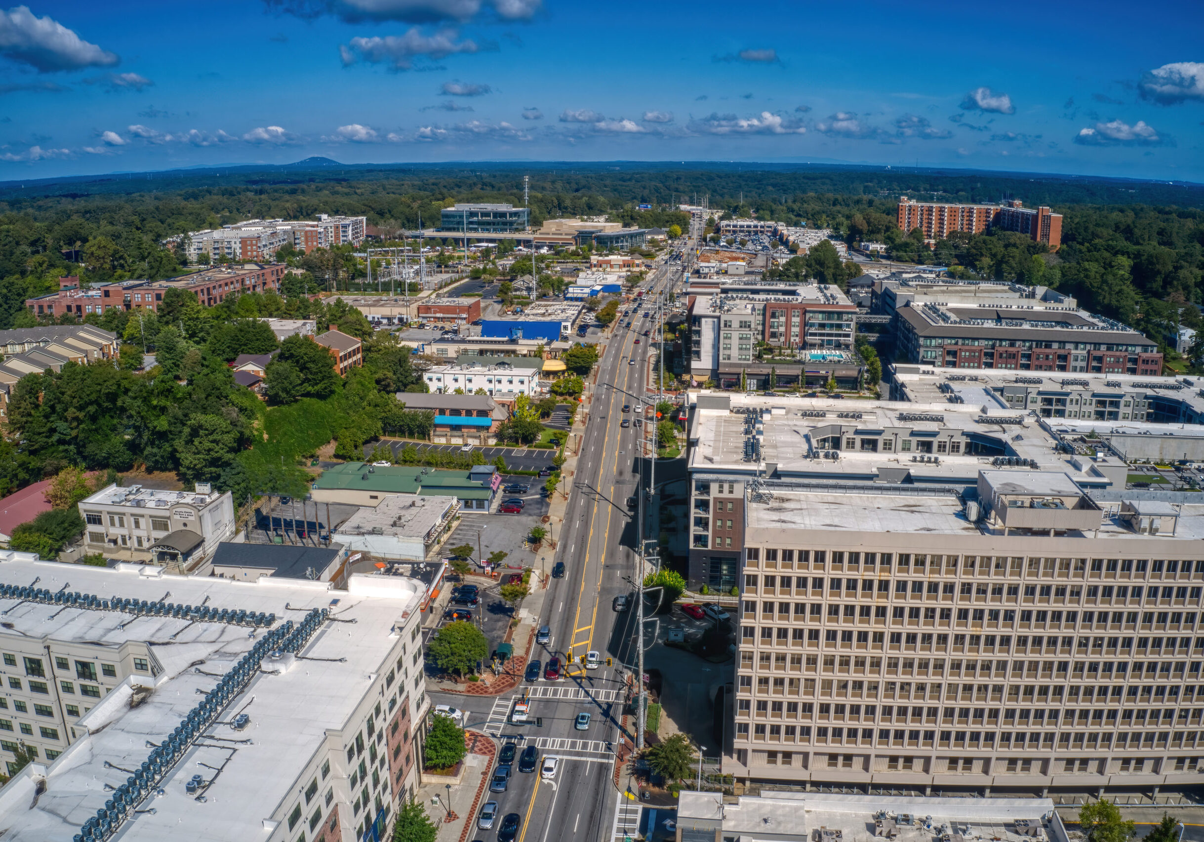 Aerial view of Atlanta suburb of Sandy Springs, Georgia, showing a busy main road lined with commercial and residential buildings.